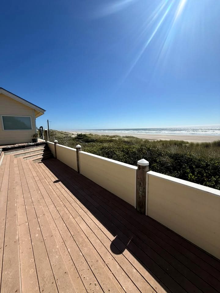 A finished oceanfront deck and railing built by Pacific Peaks Roofing, overlooking the dunes and the Oregon coast beach